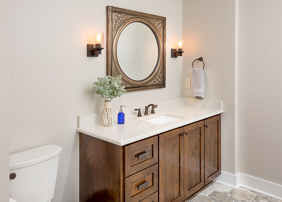 Bathroom vanity with dark wood cabinets, a white countertop, and an ornate oval mirror flanked by wall sconces.
