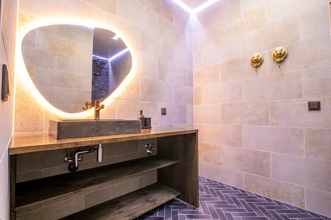 Valguseküllane vannituba hallide kahhelplaatide ja musta põrandaga loob moodsa ja elegantse atmosfääri. LED-ribaga peegel lisab luksuslikku hõngu.