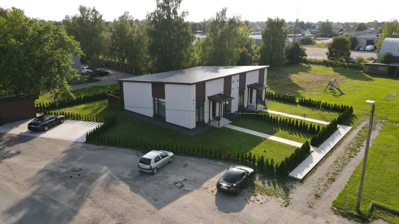 Moodne ja esteetiline välimus: Uusarendus paarismaja hallikasvalges krohvi ja pruuni puitlaudiga kombineeritud fassaadiga pakub kaasaegset ja stiilset välimust, mis sobib ideaalselt linna- või äärelinnakeskkonda. See värvikombinatsioon on elegantne ja rafineeritud, pakkudes samas hubast ja kutsuvat atmosfääri.