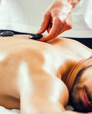 A therapist applying hot stones on a patients back for hot stone massage