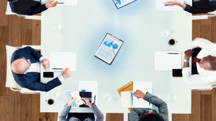 People collaborating around a table with digital devices.