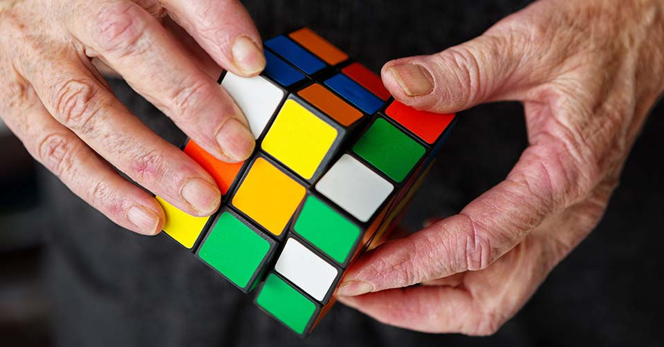 An elderly person's hands manipulate a Rubik's Cube, hopefully keeping his or her mind active. This image symbolizes the frustrations, problems and puzzles facing seniors, such as retirement planning. The cube was invented in 1974 by Erno Rubik, a Hungarian. More than 350 million have been sold.