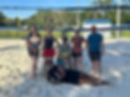 adult sand volleyball team poses at the net in Gainesville, Florida