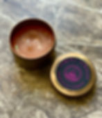 Lid open of a Vegan Candle from Gozo in a bronze or gold colored tin or container. Soy wax in rose gold.