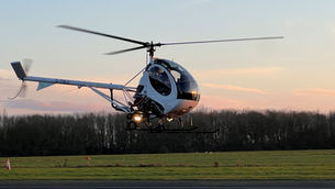 Schweizer Helicopter hovering in front of a sunset.
