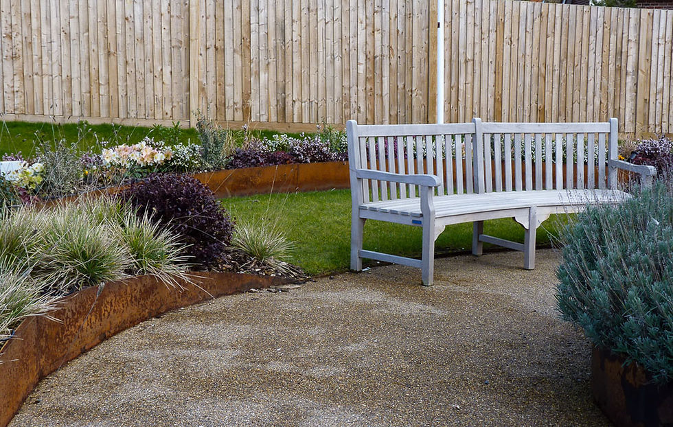 A bench surrounded by steel planters filled with plants by Bramley Apple Garden Design