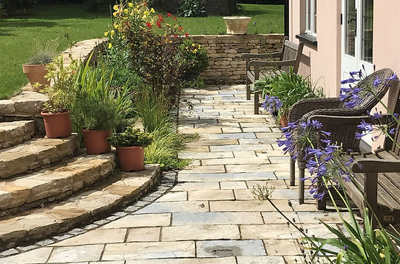 Rain garden design to improve drainage from a long path into planted borders, with clay soil improved and bold, tough planting in warm tones thriving year round.