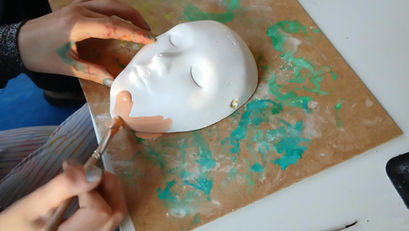 Kind bemalt Maske im Kunstunterricht