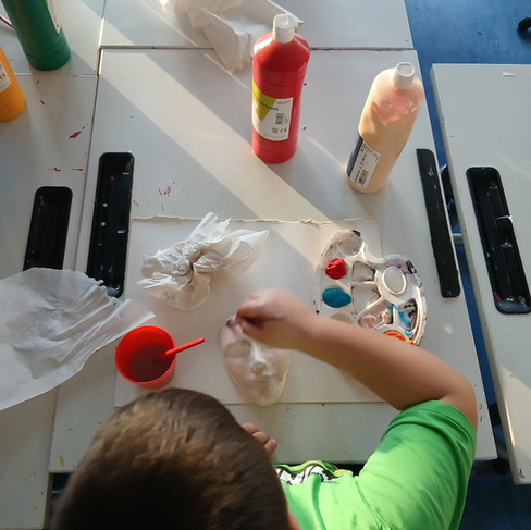 Kind bemalt Maske im Kunstunterricht