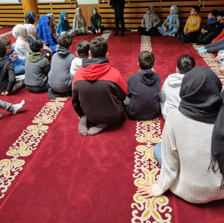 Schüler sitzen im Kreis auf Teppichboden