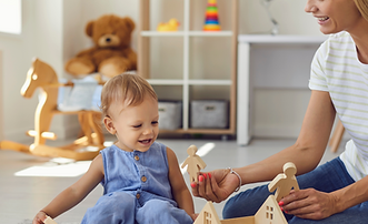 Childcare educator teaching a preschooler with educational blocks in a classroom setting