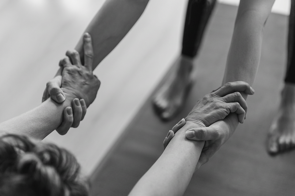 hands holding arms while two women are practicing yoga on a mat