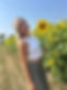 Smiling woman poses near sunflowers and fields under clear blue sky. Thompson Farm.