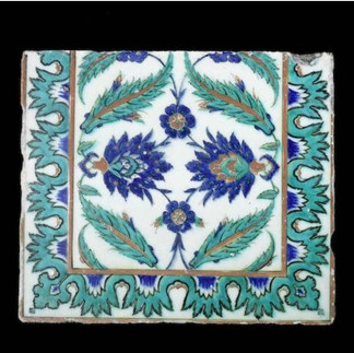 Square Iznik tile with a white background decorated with symmetrical blue flowers and turquoise leaf motifs, framed by a matching floral border. The isolated black background draws attention to the tile’s delicate Ottoman ceramic design and balanced pattern.