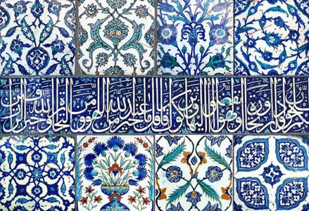 Close-up of Blue Mosque tiles featuring blue and turquoise floral patterns surrounding a horizontal band of white Arabic calligraphy on a deep blue background. The panel highlights the mosque’s intricate Ottoman tilework and the contrast between flowing script and symmetrical botanical designs.