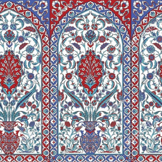 Decorative Iznik tile panel with repeating arched sections filled with red and blue floral motifs, curling leaves, and vase like forms on a white background. The symmetrical Ottoman design is framed by bold red and blue borders, and a faint watermark is visible across the image.