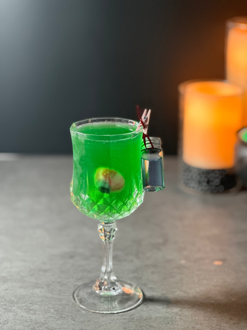 Green Halloween cocktail decorated with an elaborate dramatic garnish for a witch-themed cocktail party.