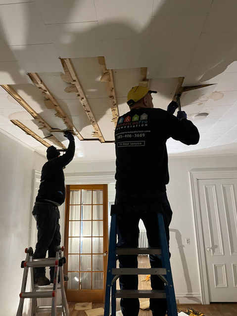 Specialists are ripping out a ceiling after a multi story water loss.