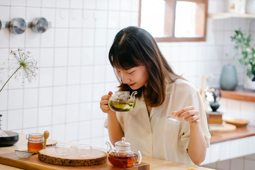 une femme de quarante ans d'origine asiatique qui est dans sa cuisine et sent la théière dans laquelle elle a préparé une tisane, elle sourit