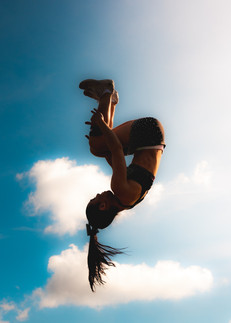 Cheerleading flyer performing a basket toss during a team practice.