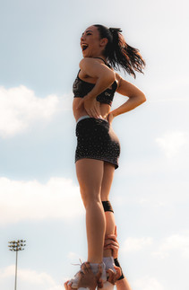 Cheerleading flyer holding a block stunt with perfect balance during a stunt.