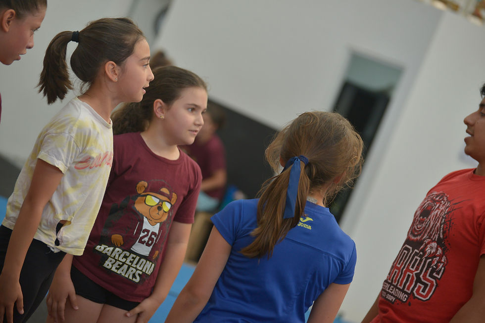 Entrenador de Barcelona Bears explicando el primer entrenamiento de cheerleading a un grupo de niñas con ropa deportiva.