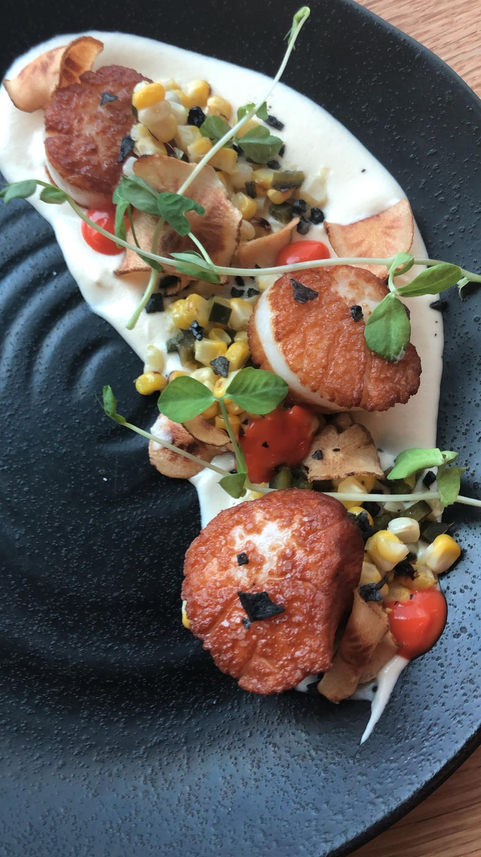 a close up of a plate of food with scallops corn and tomatoes