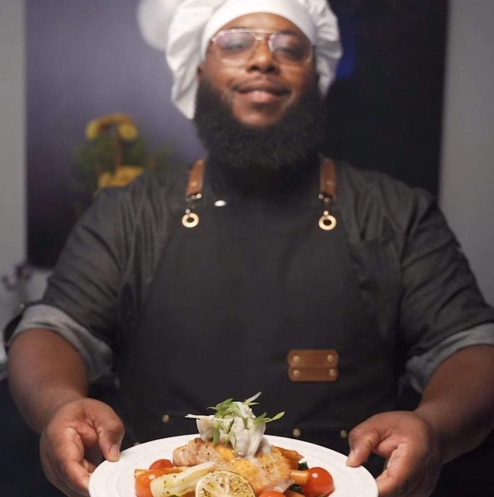 a man in a chef 's hat is holding a plate of food