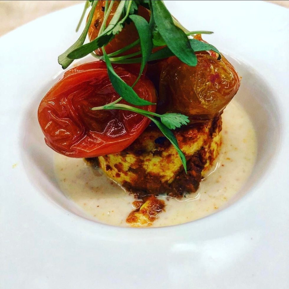 a plate of food with tomatoes and greens on top
