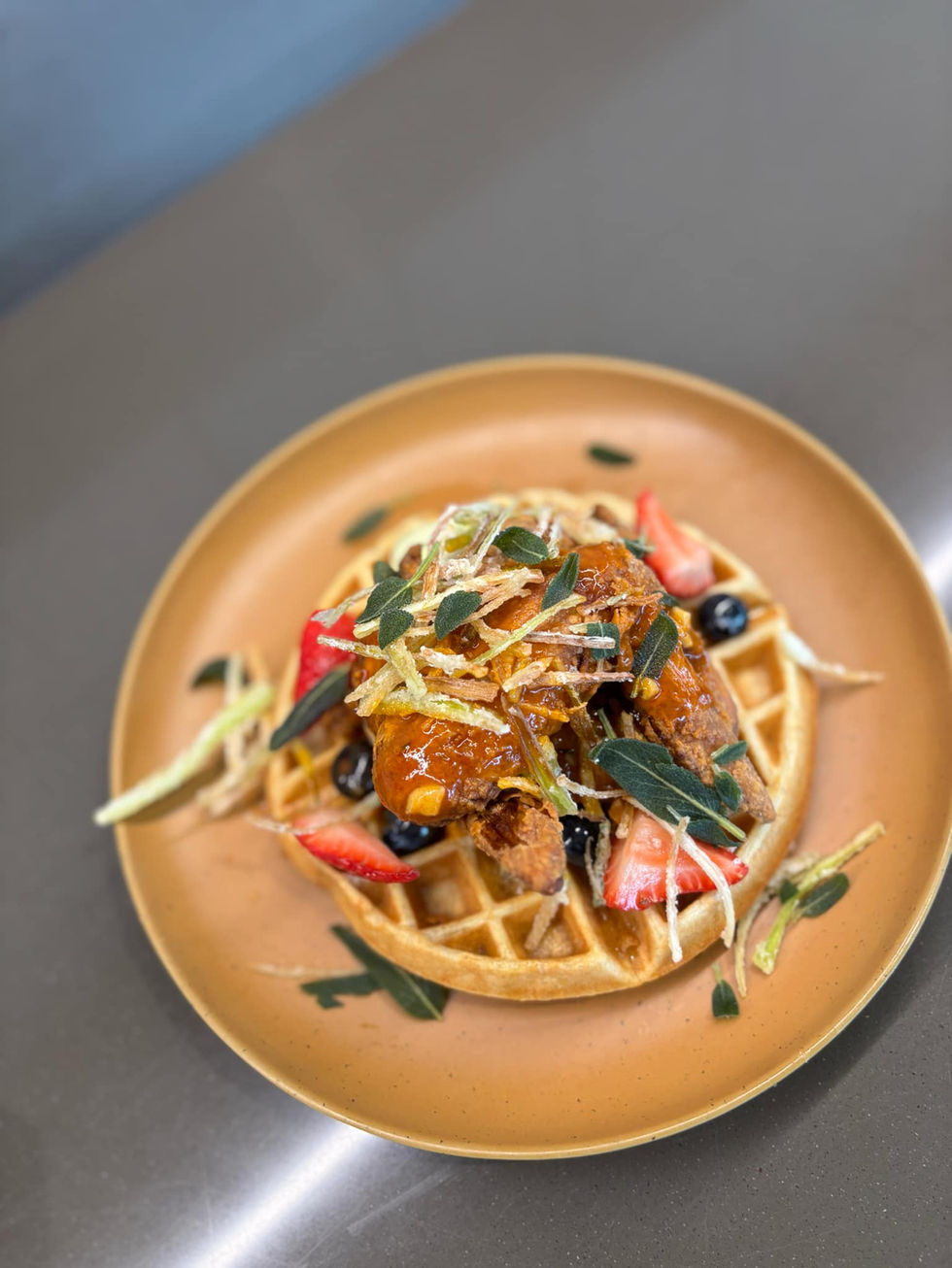 a waffle with chicken and strawberries on it on a plate
