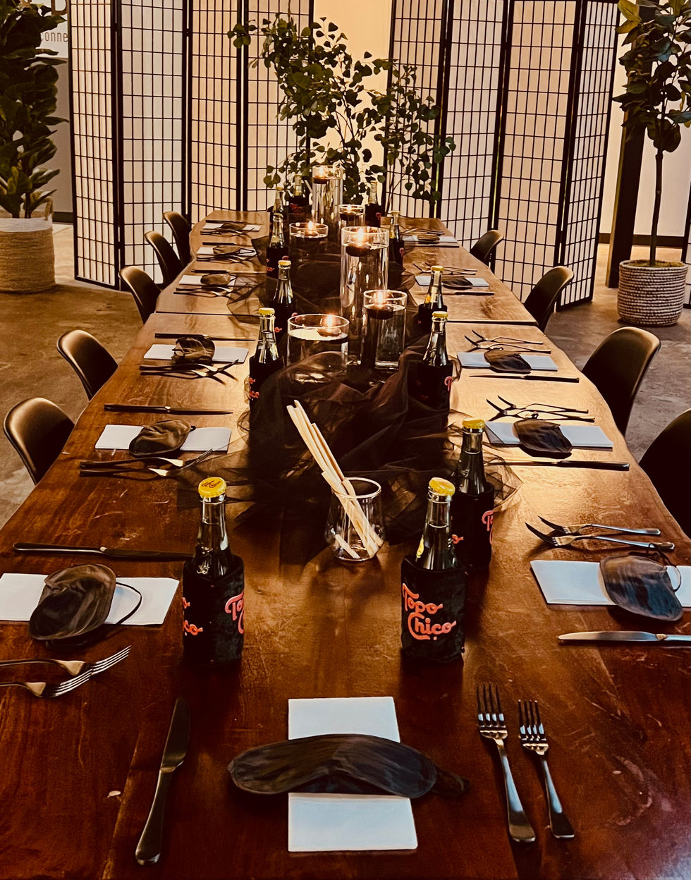 a long wooden table with bottles of pepper chico on it