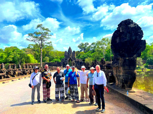 Tour guide with a group of visitors at the South Gate of Angkor Thom, with stone statues and naga balustrades in Siem Reap, Cambodia.