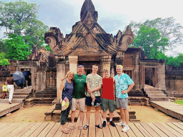 Tour group standing in front of Banteay Srei Temple in Siem Reap, Cambodia, known for its pink sandstone and intricate carvings.