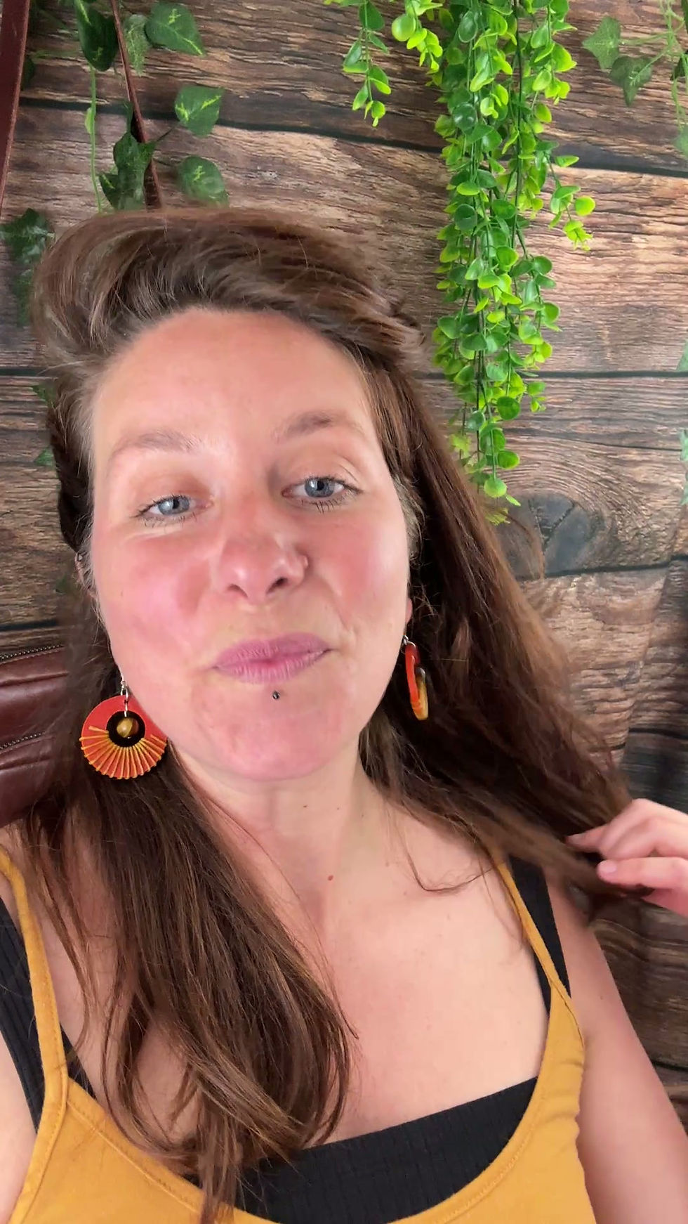 Miniature : Vidéo d’une femme portant les boucles d’oreilles artisanales Sundara en cuir orange et pierre Œil de Tigre en mouvement
