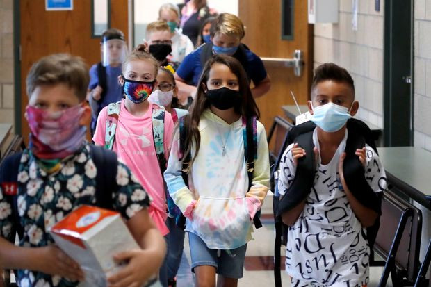 Elementary school students in masks in the hallway at school, attending school during a pandemic