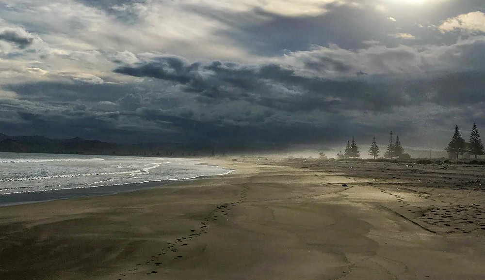 walking on the beach in Gisborne North Island New Zealand at sunset with cloudy skies and a storm rolling in, on the beach, South Pacific, discover golden sand beach of New Zealand, travel new zealand, travel the world, explore north island