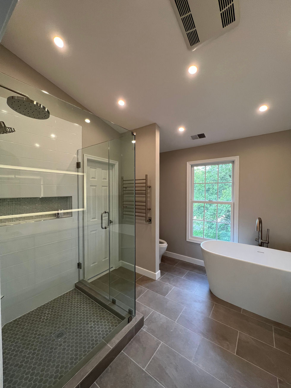 Freestanding soaker tub beside a glass walk-in shower in a Potomac bathroom