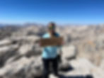 A girl holding a Mount Langley sign at the summit