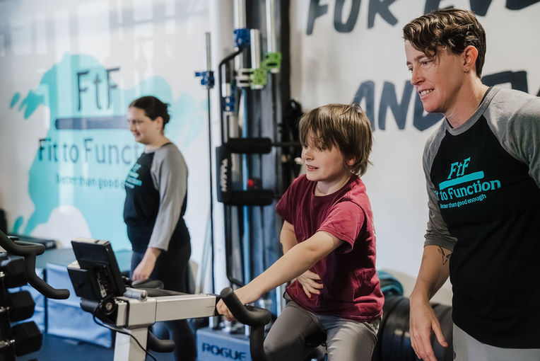 Boy exercises with trainers at Fit to Function gym, the logo visible.