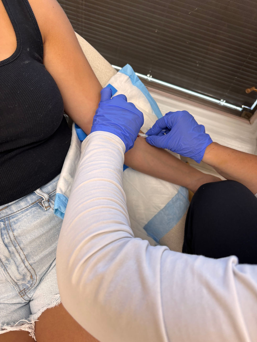 in blue gloves, administers the injection. The scene conveys a clinical setting.