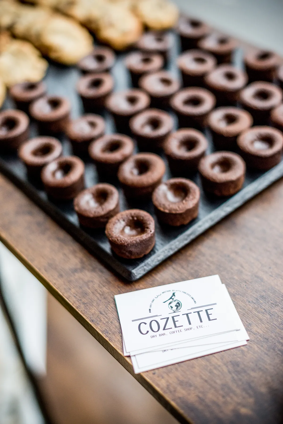 Photographe événementiel Chambéry - petites pâtisseries au chocolat posées sur une plaque noire sur une table en bois