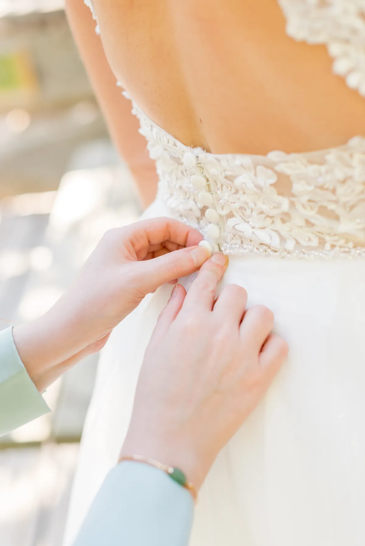 Photographe mariage Annecy – détail mains boutonnent robe mariée préparatifs