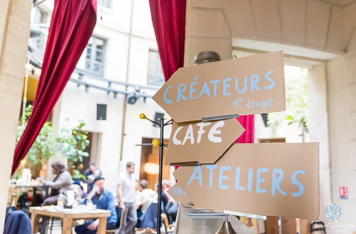 Photographe événementiel Aix-les-Bains. Des panneaux indiquant "Créateurs", "Café", "Ateliers" dans un café animé.