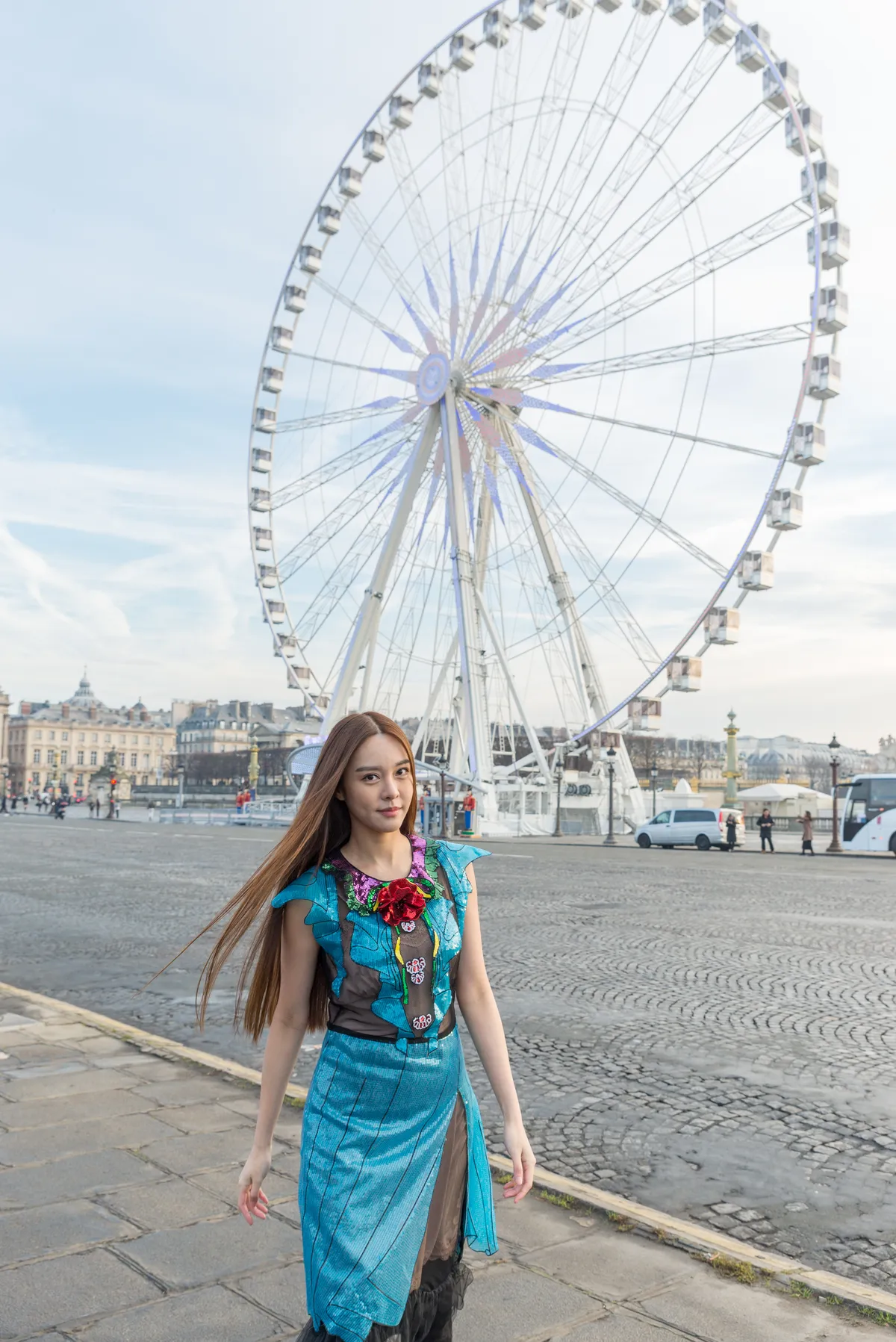 Photographe - jeune femme élégante marche devant la grande roue de Paris