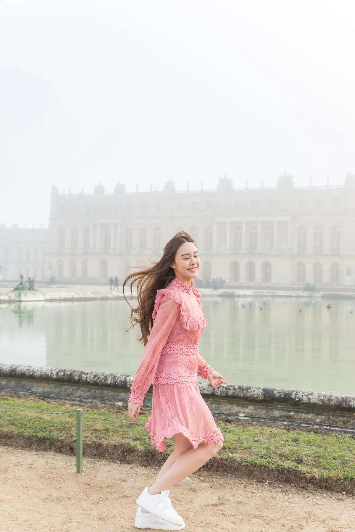 Photographe - jeune femme sautillant dans les jardins du Château de Versailles