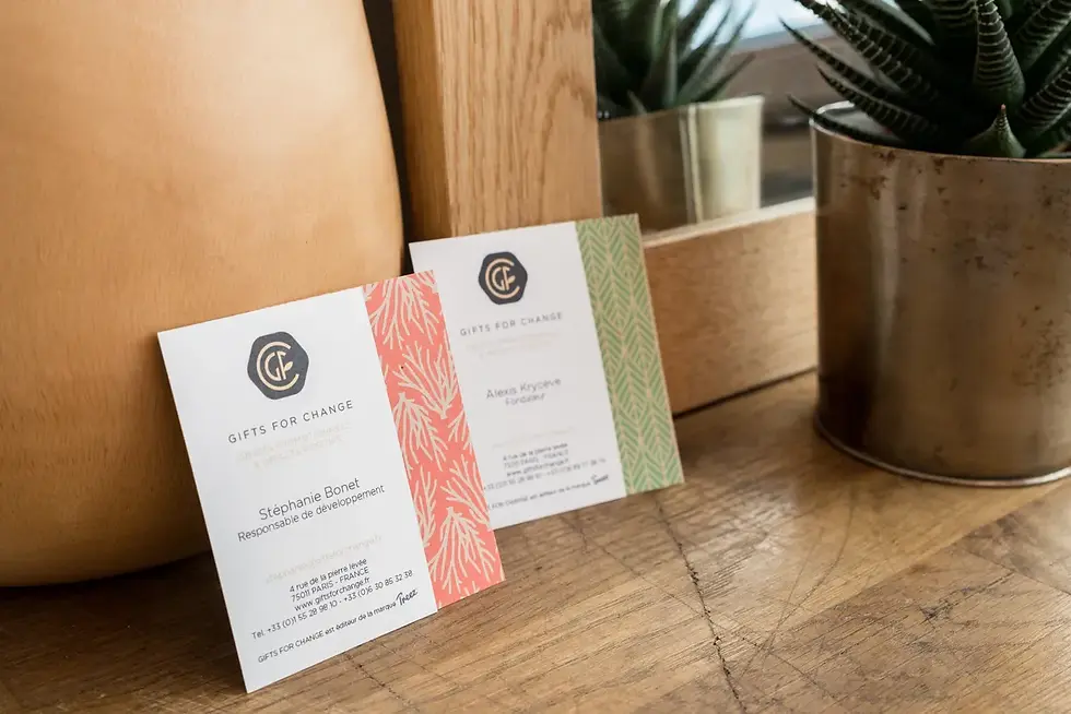 Photographe entreprise Savoie - cartes de visite "Gifts for Change" sur une table en bois, ornées de motifs rouges et verts.
