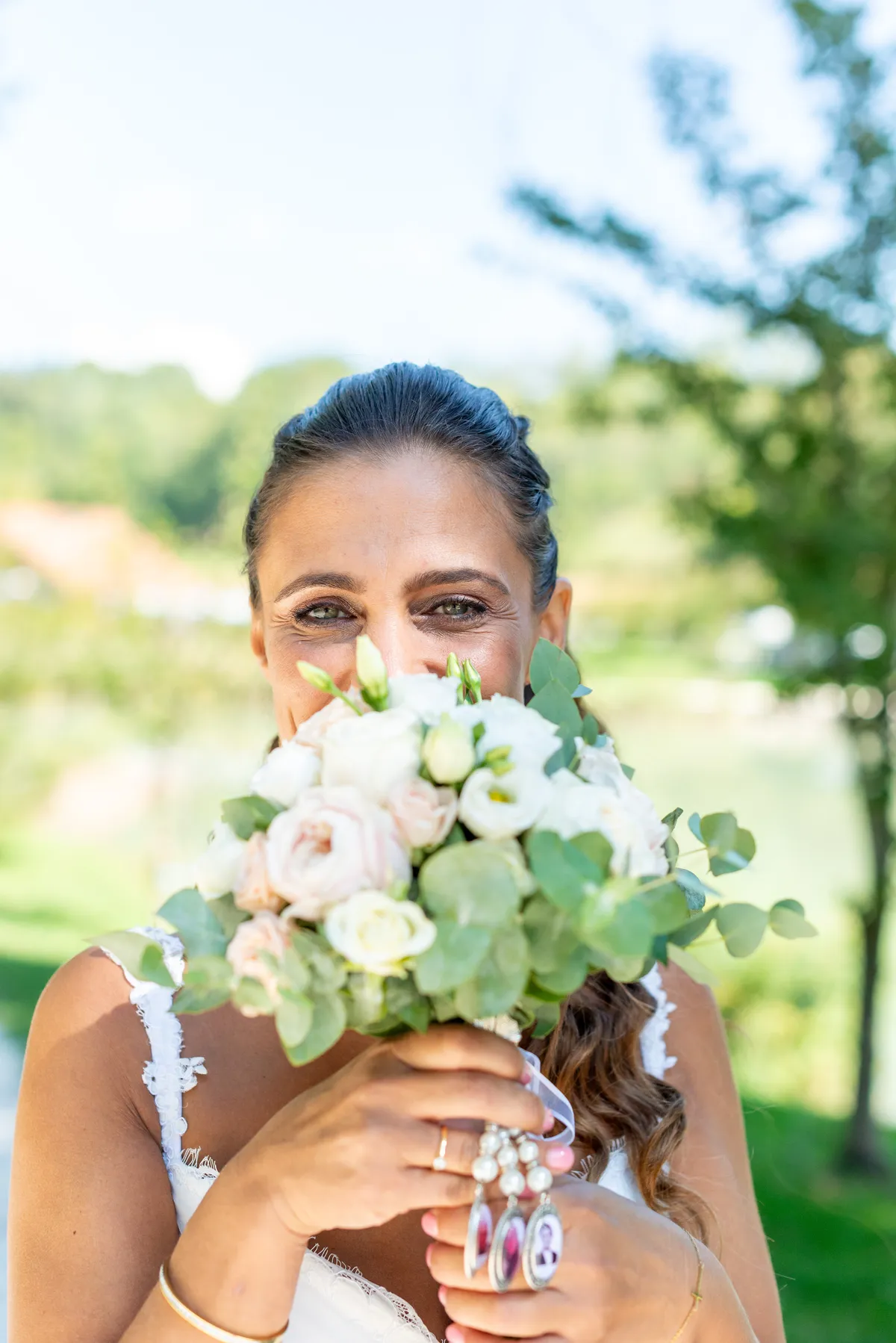 Portrait de la mariée derrière son bouquet de fleurs