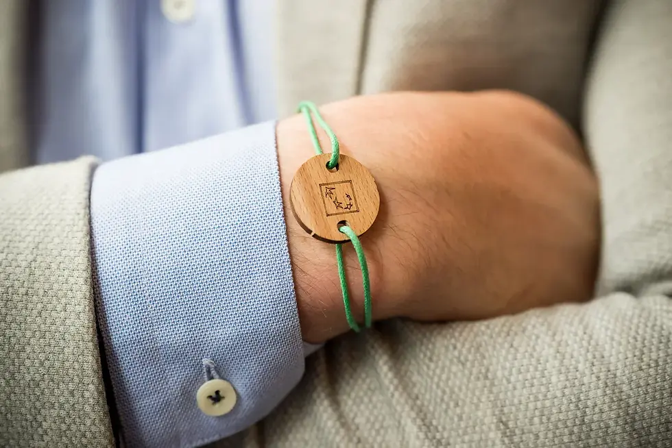 Photographe entreprise Chambéry - poigné d'homme en costume beige avec chemise bleue portant un bracelet en bois et fil vert.