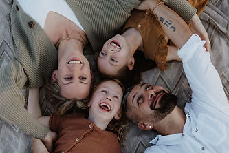 Tania Kühnst liegt mit ihrer Familie gemeinsam auf einer Decke und lacht – authentische Familienfotografie in der Natur
