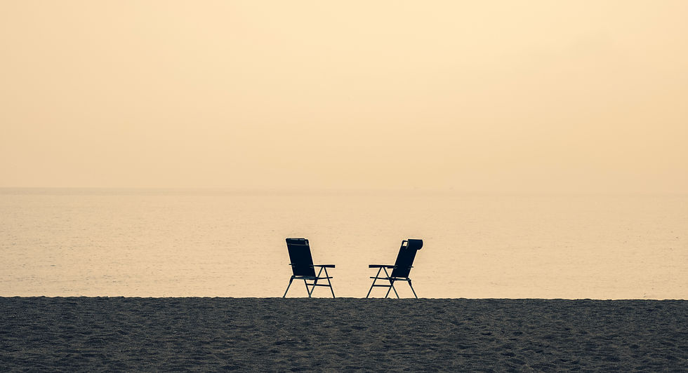 Solidão. Duas cadeiras de praia na areia, ao fundo o mar.